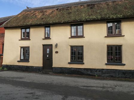 A house with a thatched roof and windows at Bridge Cottage in Budleigh Salterton