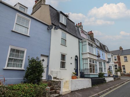 A row of terraced houses with different colored facades along a street at Old Harbour Townhouse in Weymouth