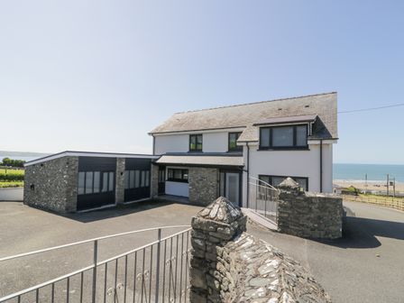 A two-story house with a stone garage and a driveway near the coast at Melin Y Plas in Llanaber