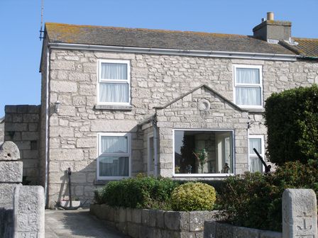 A stone house with windows and a garden with bushes in front at Anchor Cottage in Weston Portland