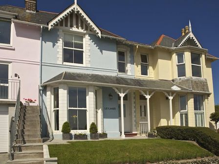 A front view of a row of attached houses with a small lawn and stairs at Leylands in Salcombe