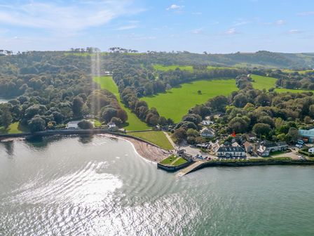 An aerial view of a coastal village with houses trees and green fields by the water at Seascape in Kingsand