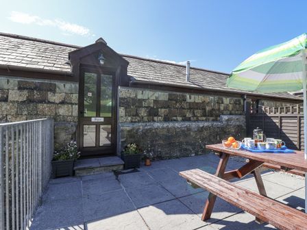 An outdoor seating area with a table and umbrella at The Byre Common Moor near Liskeard