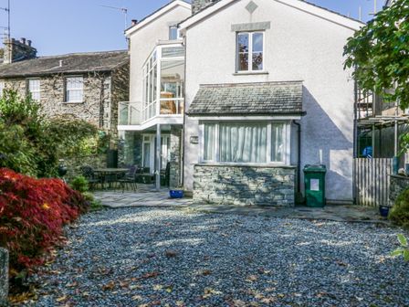A house with a pebble driveway and patio furniture in the garden at Blue Hill House in Ambleside