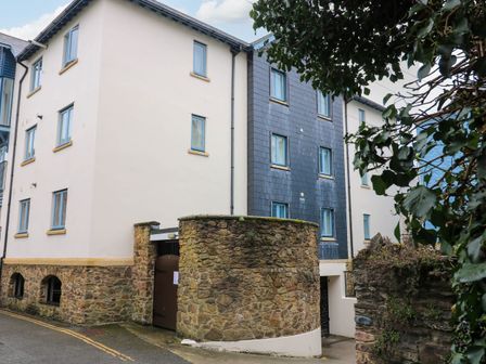 An exterior view of a multi-story building with stone walls and blue window frames at 8 Dartmouth House in Dartmouth