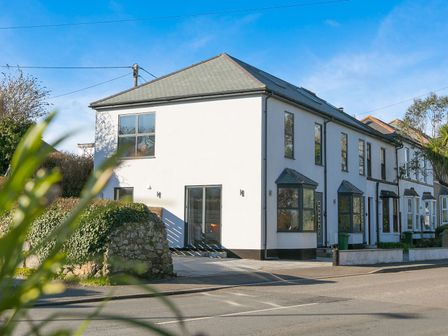 A white two-story house with multiple windows and a bay window at Nova Cottage in Carbis Bay