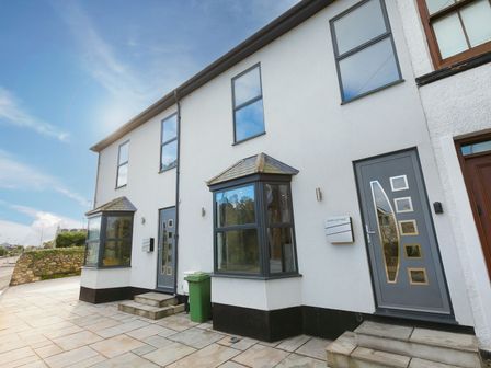 The exterior of a white two-story building with two grey entrance doors and two bay windows at Avon Cottage in Carbis Bay