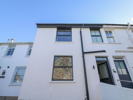 White exterior of a two-story house with black framed windows and an open door at 2 Salubrious Terrace in St Ives