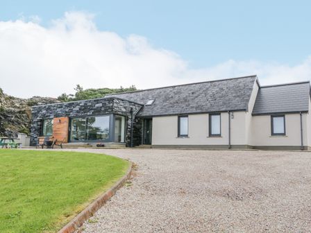 A modern house with stone and white walls gravel driveway and green lawn at Ballyness Bay in Killult Upper near Gortahork County Donegal