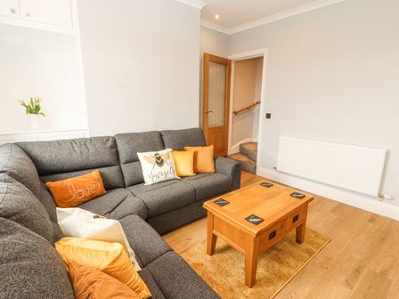 A living room with a grey sectional sofa and cushions around a wooden coffee table at Grace House in Silloth