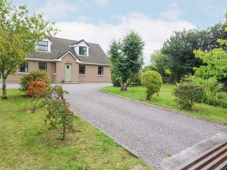 A driveway leading to a house with a green lawn and trees at Knockbrack in Lonart near Killorglin County Kerry