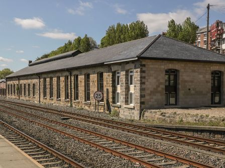 A stone building with multiple windows next to railway tracks and a 25 speed limit sign at Flying Scotsman @ Engine Shed in Whitby