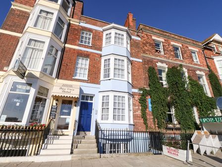 Front entrance of Bay View Hotel with brick buildings and ivy on walls in Weymouth