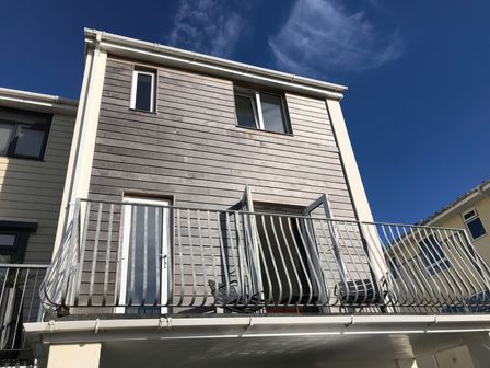 Exterior view of a two-story house with wooden paneling a balcony and metal railing at 6 Inveravon in Christchurch