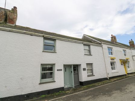 A row of white cottages with windows and doors along a street at Penhaven in Coverack