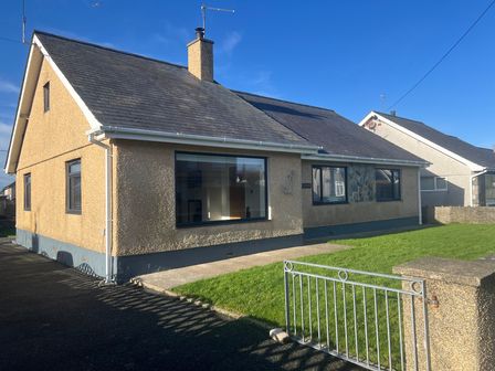 A house with a large window and grass in front at Morannedd in Morfa Nefyn