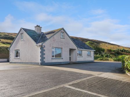 A single story house with multiple windows and a driveway in a rural area at Teach Annie Agus Paddy in Meenlaragh near Gortahork County Donegal