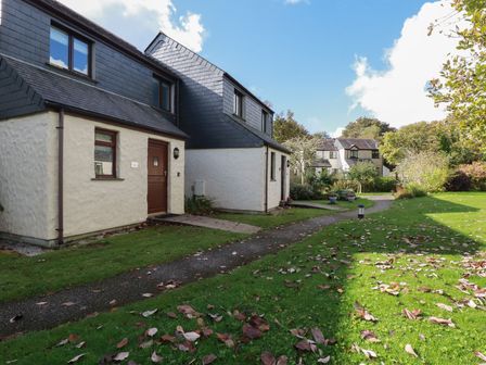 Houses with slate roofs along a pathway and grass with fallen leaves at Coombe Cottage in Falmouth