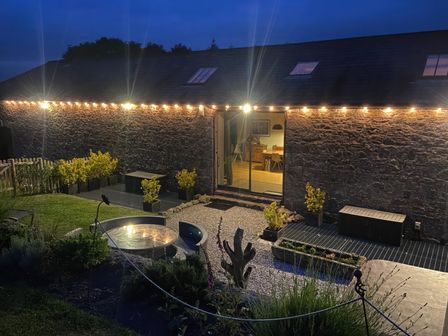A garden with plants and seating at Halshanger Barn near Ashburton