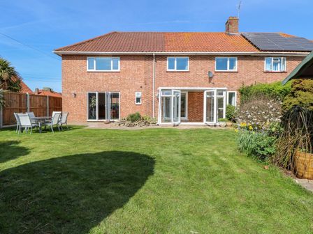A backyard garden with a grass lawn patio doors and outdoor seating at Cedar View in Hainford near Coltishall
