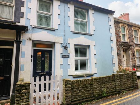 Front view of a blue house with white trim a dark door and a white picket fence at Rushfield in St Dogmaels North Pembrokeshire