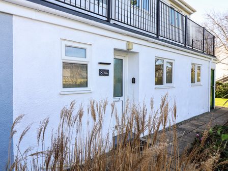 A white building exterior with three windows and a door with a sign reading Beachcomber and the number 8 at Beachcomber Maer near Bude