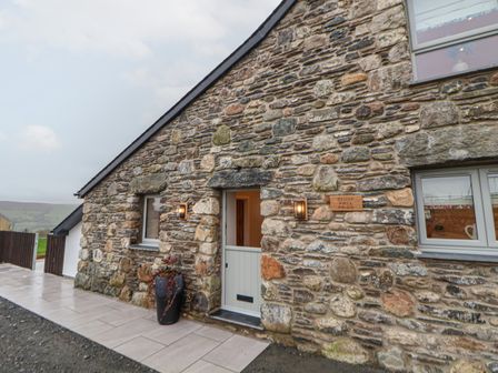 A stone building exterior with a half door and two windows at Beudy Pwll Pridd in Llangollen