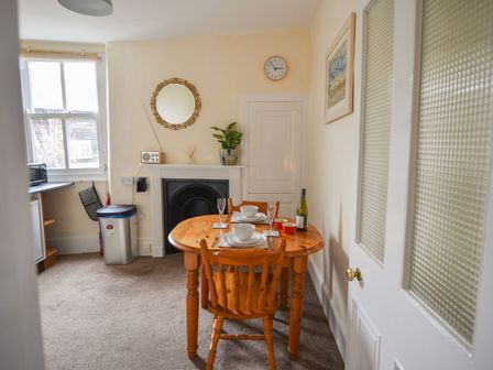 A dining area with a wooden table set for two and a small fireplace in the corner at The Annexe St Agnes House Lyme Regis
