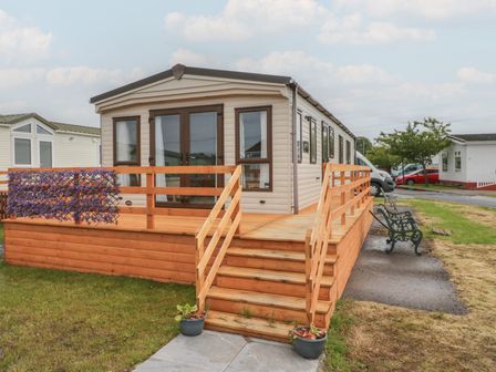 A mobile home with a deck and bench at Aspen in Denny