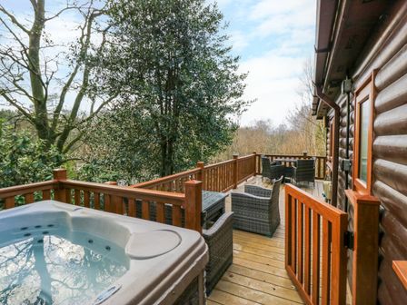 A wooden deck with a hot tub and outdoor seating next to a log cabin at Esk Pike 9 Skiptory Howe White Cross Bay near Windermere
