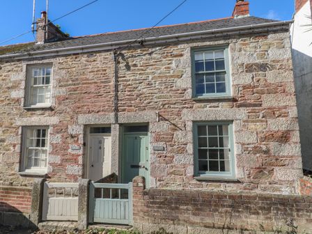A stone cottage with two front doors and windows and small gates at Apple Tree Cottage in Gweek