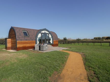 A small wooden cabin with curved roof and outdoor seating on a grassy field at Leadon View Willow in Upleadon near Newent