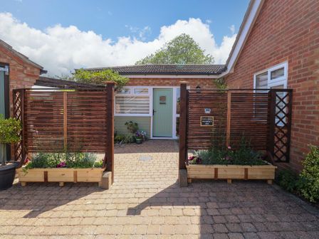 An entrance with a fence and plant beds at Rainbow's End in Swanton Morley