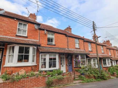 A row of red brick terraced houses with tiled roofs and small front gardens at Puffins in Sidmouth