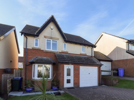 A detached house with brick and cream walls a white garage door and a bay window at Coastal Retreat in Seahouses