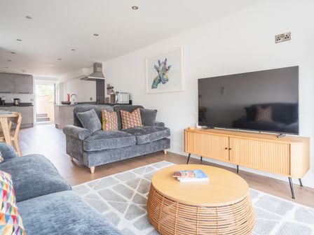 A living room with grey sofas a wooden coffee table and a TV on a wooden cabinet at Hoheck in Abersoch