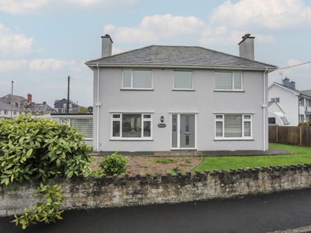 A two-story house with a garden and a stone wall in front at Monarfon in Criccieth