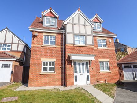 A front view of a brick house with white windows a white front door and a small lawn at 9 Beckett Close in Colwyn Bay