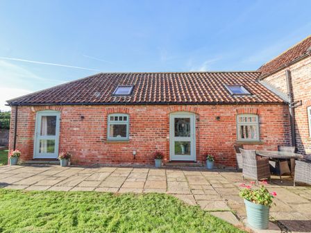 A brick building with two doors and three windows with a tiled roof and outdoor seating at The Old Stable Great Hatfield near Hornsea