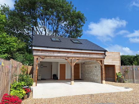 A carport with gravel driveway and trees at The Halt in Maiden Newton
