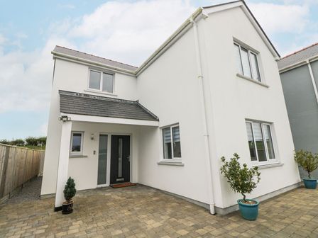 A front view of a white two-story house with paving stones and potted plants at Golygfa Hafan in Little Haven