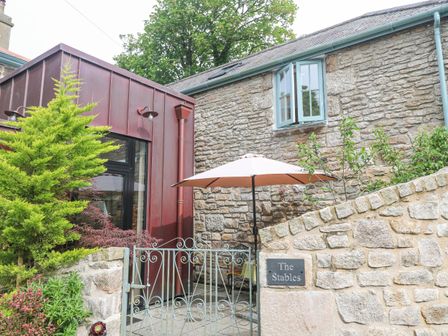 An outdoor area with a stone wall and an umbrella at The Stables in St Just