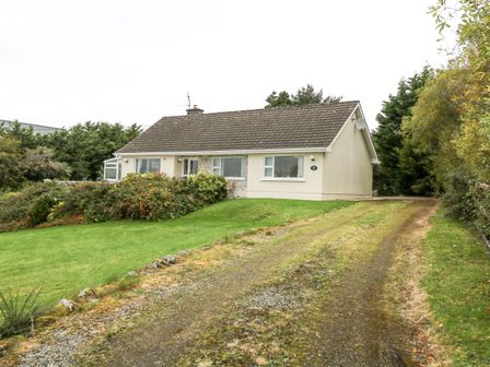 A single story house with a tiled roof surrounded by grass and shrubs at Lakeview Lodge in Knockmore County Mayo