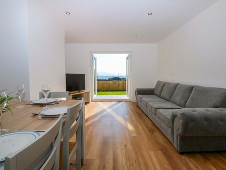 A living room with a dining table and a sofa at 15 Llys Tegeirian in Llangristiolus near Llangefni