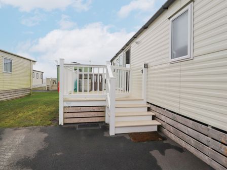 An exterior view of a static caravan with white steps leading to a small deck area at Plot LD19 in Heysham