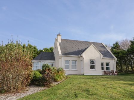 A detached house with a grey roof and white walls surrounded by grass and bushes at Horn Head View in Carrigart County Donegal