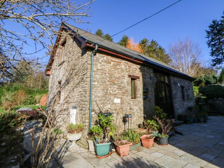A stone house with potted plants and a pathway at Maggie's Barn in Brecon