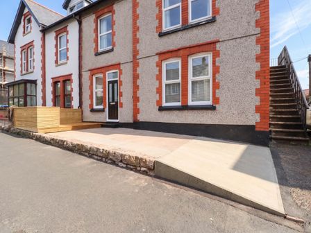 A house with a wooden deck and concrete area at Flat 1 Rhos-On-Sea