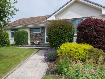 A front yard with bushes flowers and a pathway leading to a house entrance at Curlew in Rock