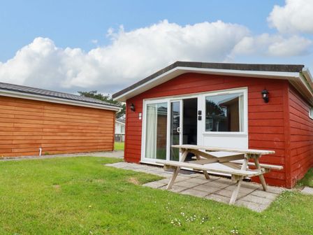 A cabin with a picnic table and grass at H2 Atlantic Bay Holiday Park in Padstow